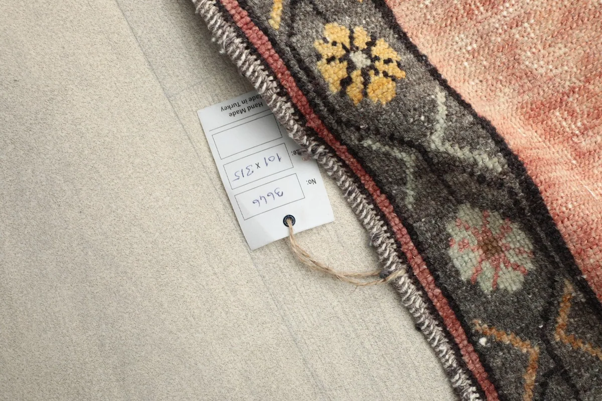 Close-up of the rug's border with a size tag, showing the hand-knotted edge and wool texture