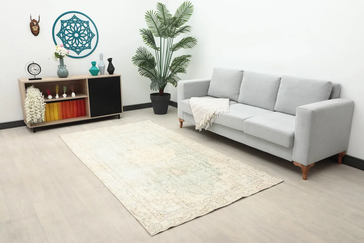 Vintage Anatolian rug placed in a living room setup with a gray sofa and decor