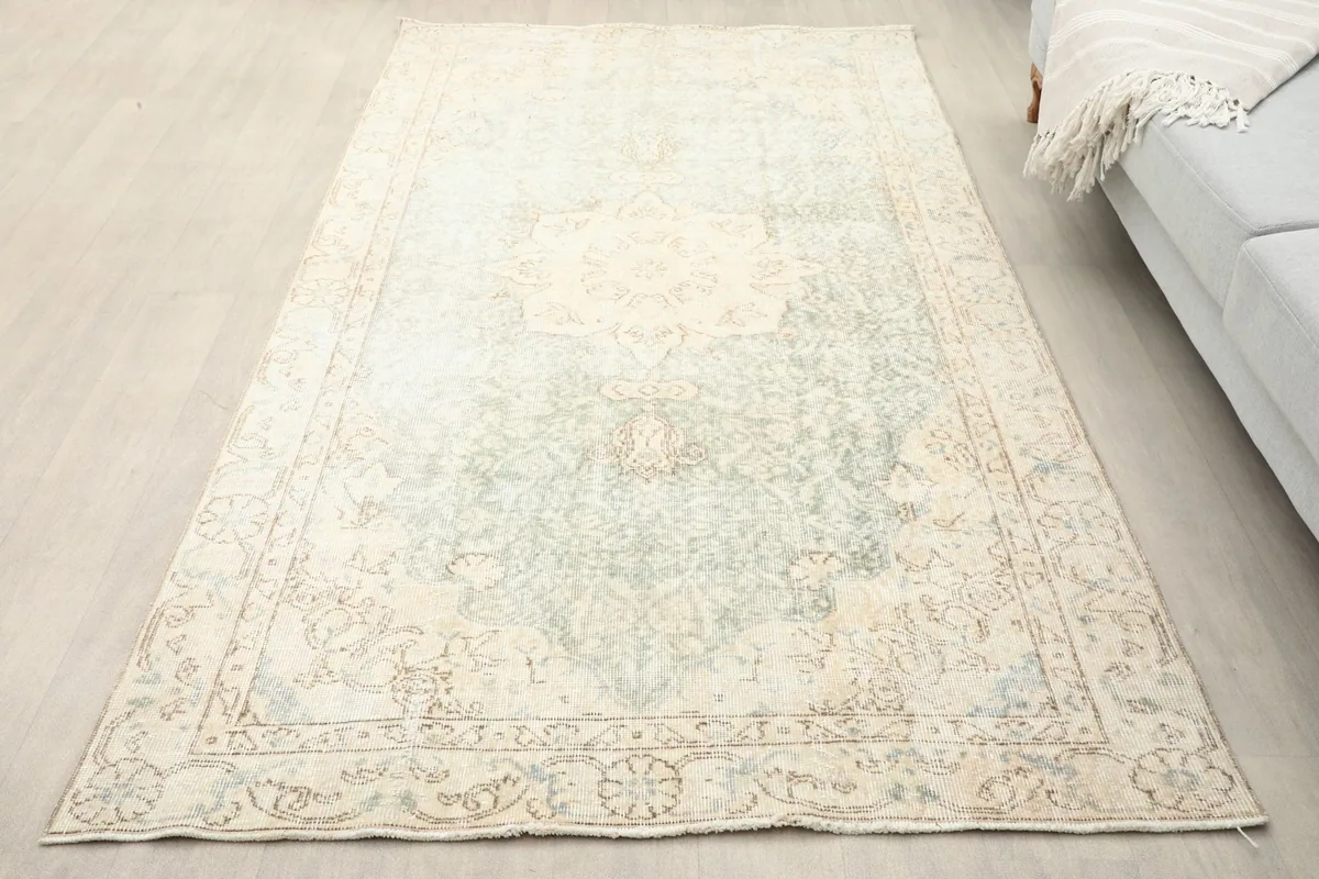 Overhead view of the vintage rug on a light floor, showing its size and faded colors