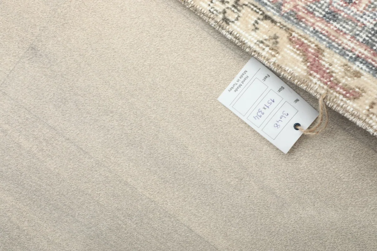 Corner of the rug with a tag, showing the reverse side and the hand-finished edge