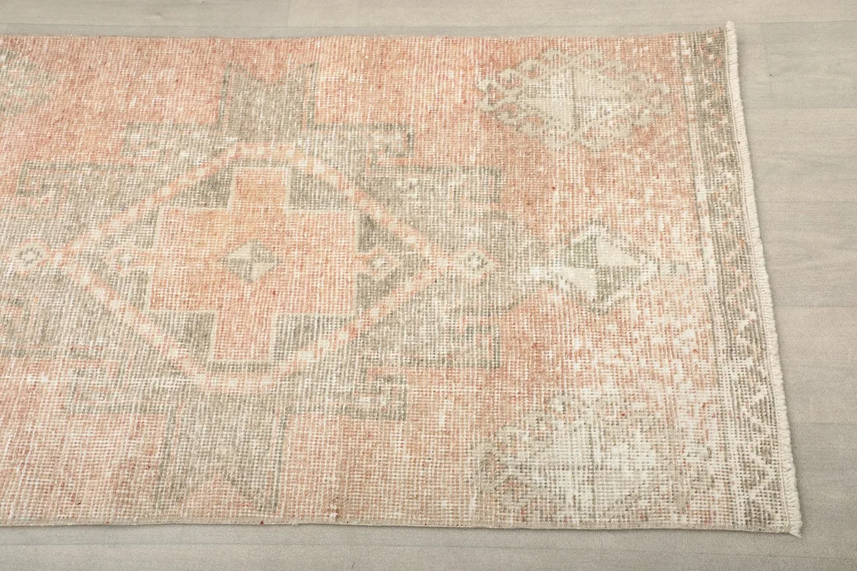 Close-up detail of the rose and gray geometric tribal pattern on the rug