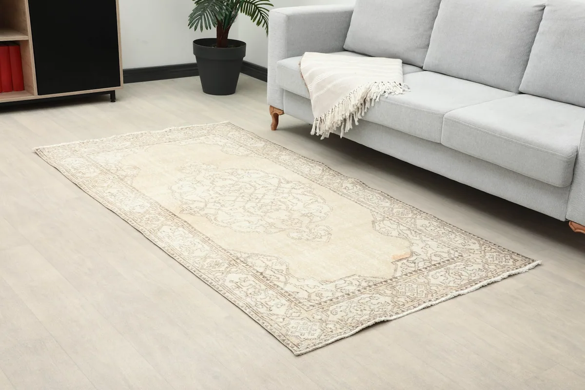 Angled view of the ivory geometric rug in a room, showing its placement next to a sofa.