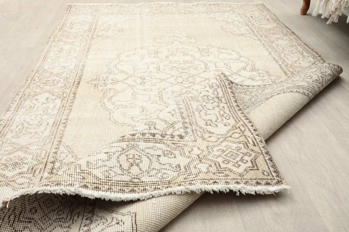 Rolled-up edge of the rug, displaying the short, natural cotton fringe.