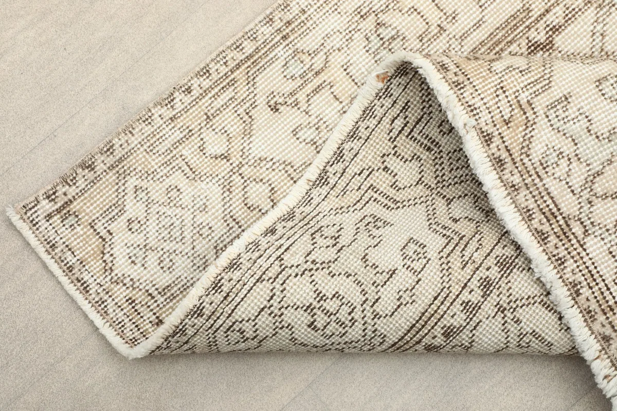 Folded corner of the rug, showing the wool pile and cotton foundation.