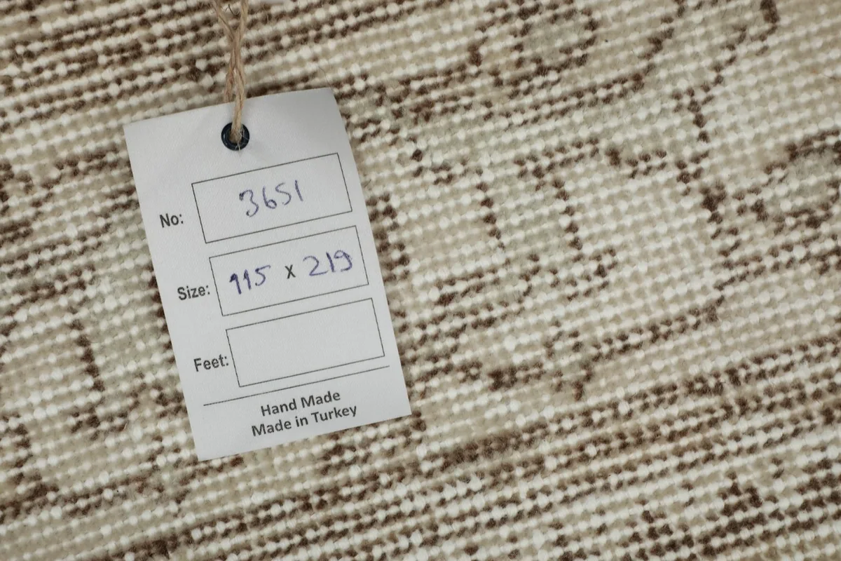 Close-up of the rug's tag, showing item number and dimensions 115 x 219 cm.