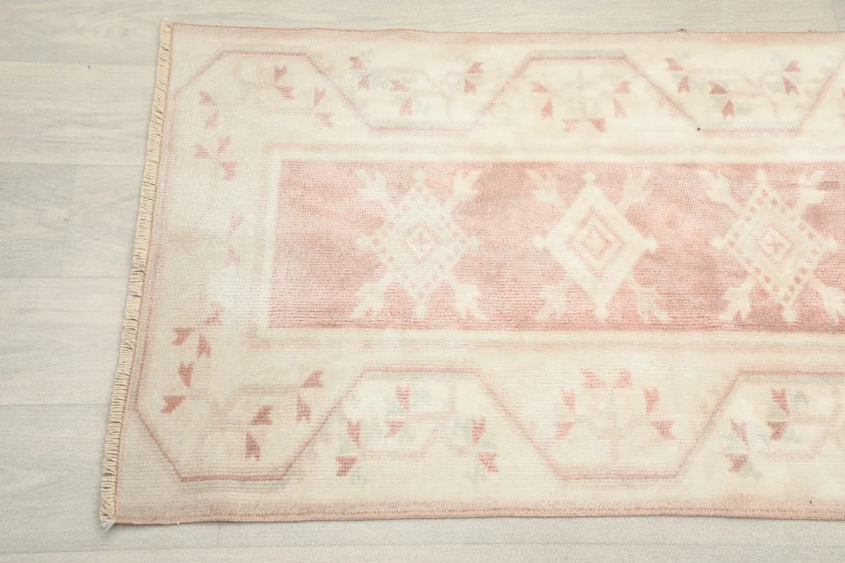 Detailed view of the rug's ivory border with small rose tribal motifs