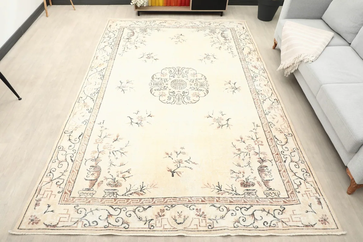Ivory vintage Anatolian rug displayed in a living room setting next to a light gray sofa.