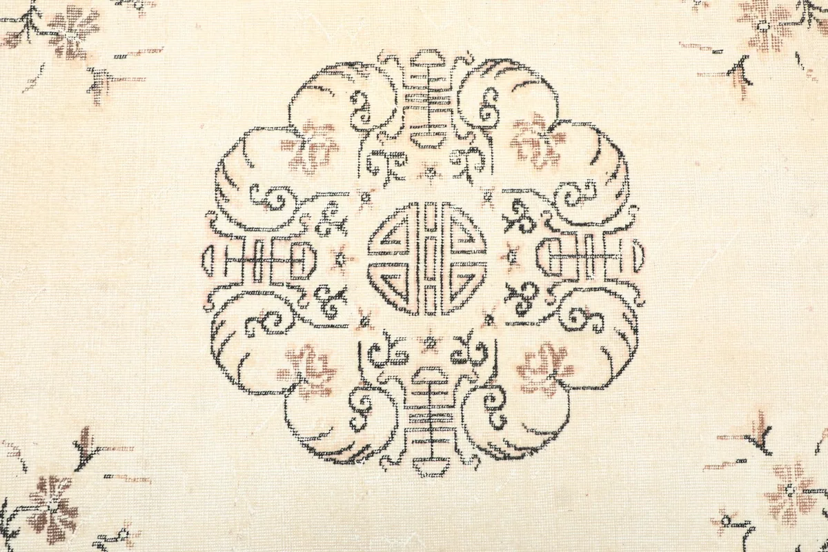 Detailed view of the central medallion design on the ivory field of the rug.