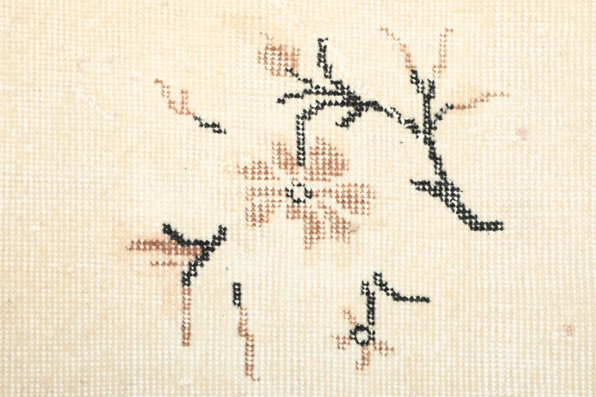 Close-up showing the low wool pile and hand-knotted texture of the rug with floral details.