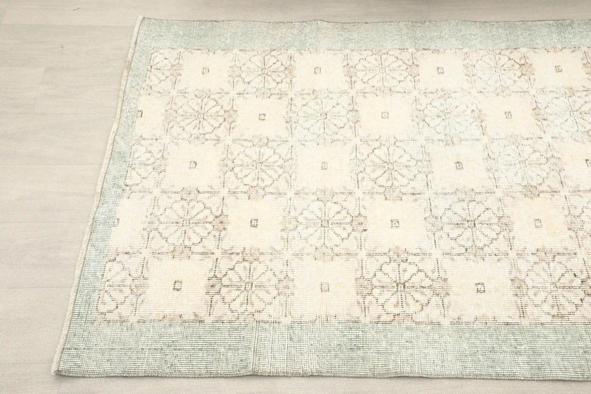 Another angle view of the ivory vintage rug, showing the faded geometric floral motifs