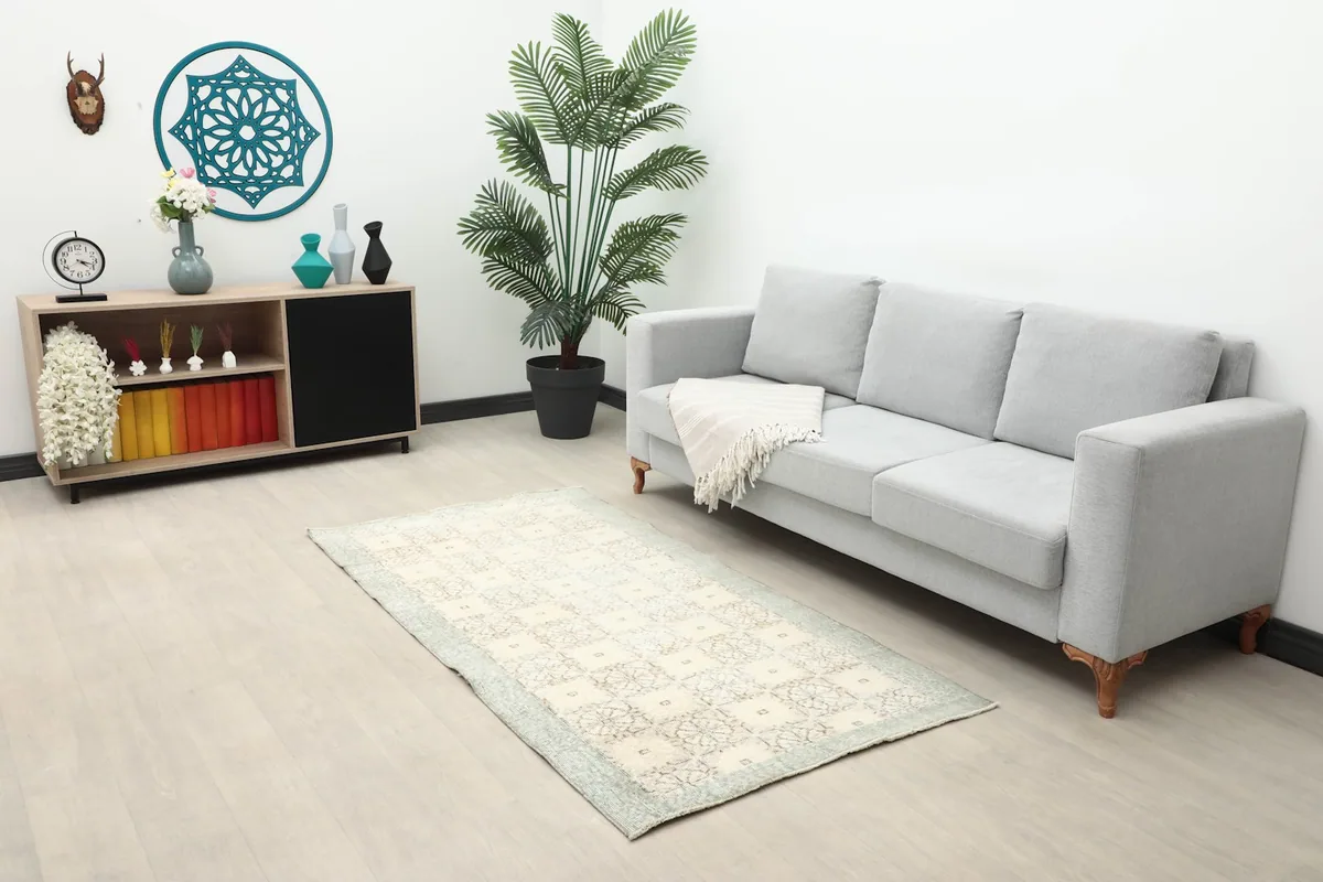 Ivory geometric floral rug styled in a living room with a gray sofa and wooden furniture