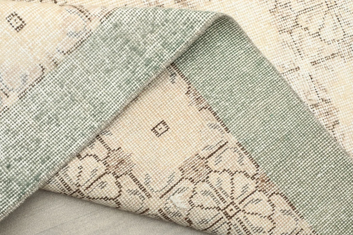 View of the rug's backside and folded edge, showing the cotton foundation