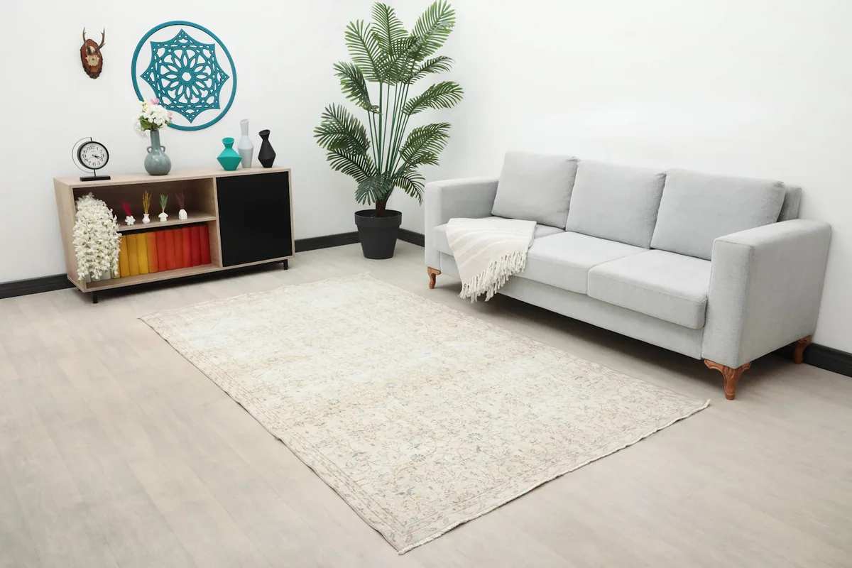 Cream floral rug in a living room setting with a light gray sofa and modern decor.