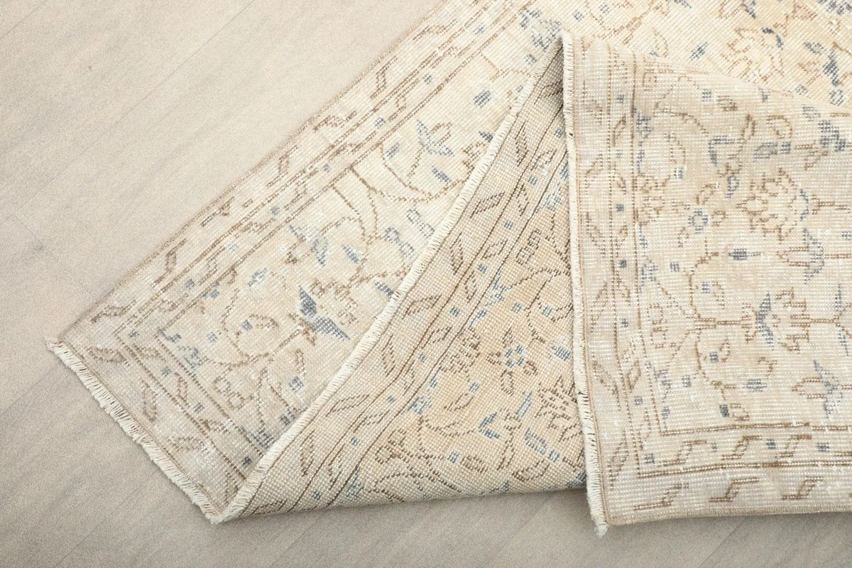 Corner of the rug folded back, showing the back of the rug and the border design.