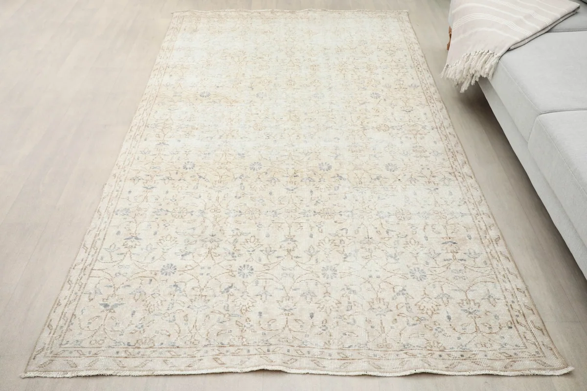 Overhead perspective of the cream vintage rug laid out on a light wood floor.