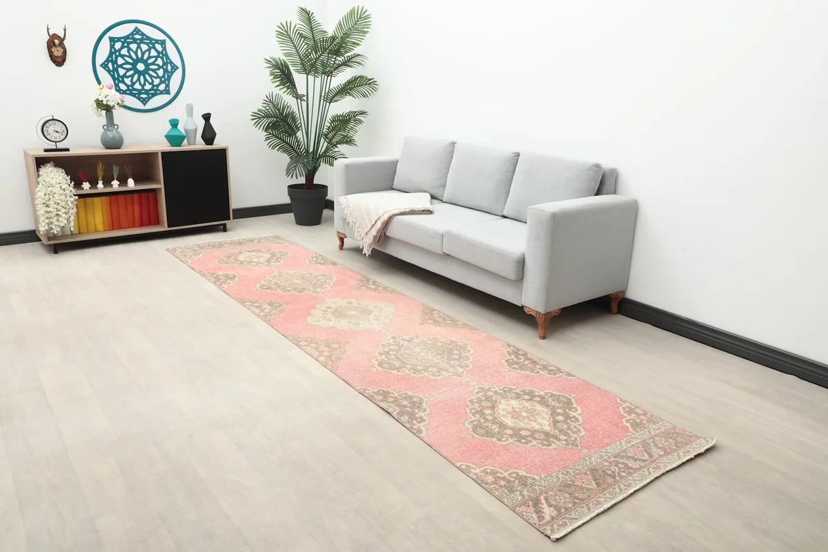 Long view of the rose runner rug in a modern living space with a gray sofa and plant.