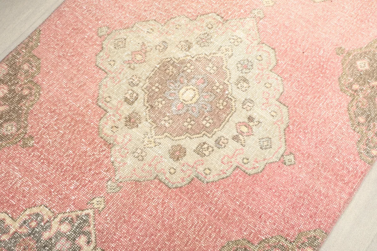 Overhead detail of a central medallion on the rose vintage runner, showing its brown and ivory elements.