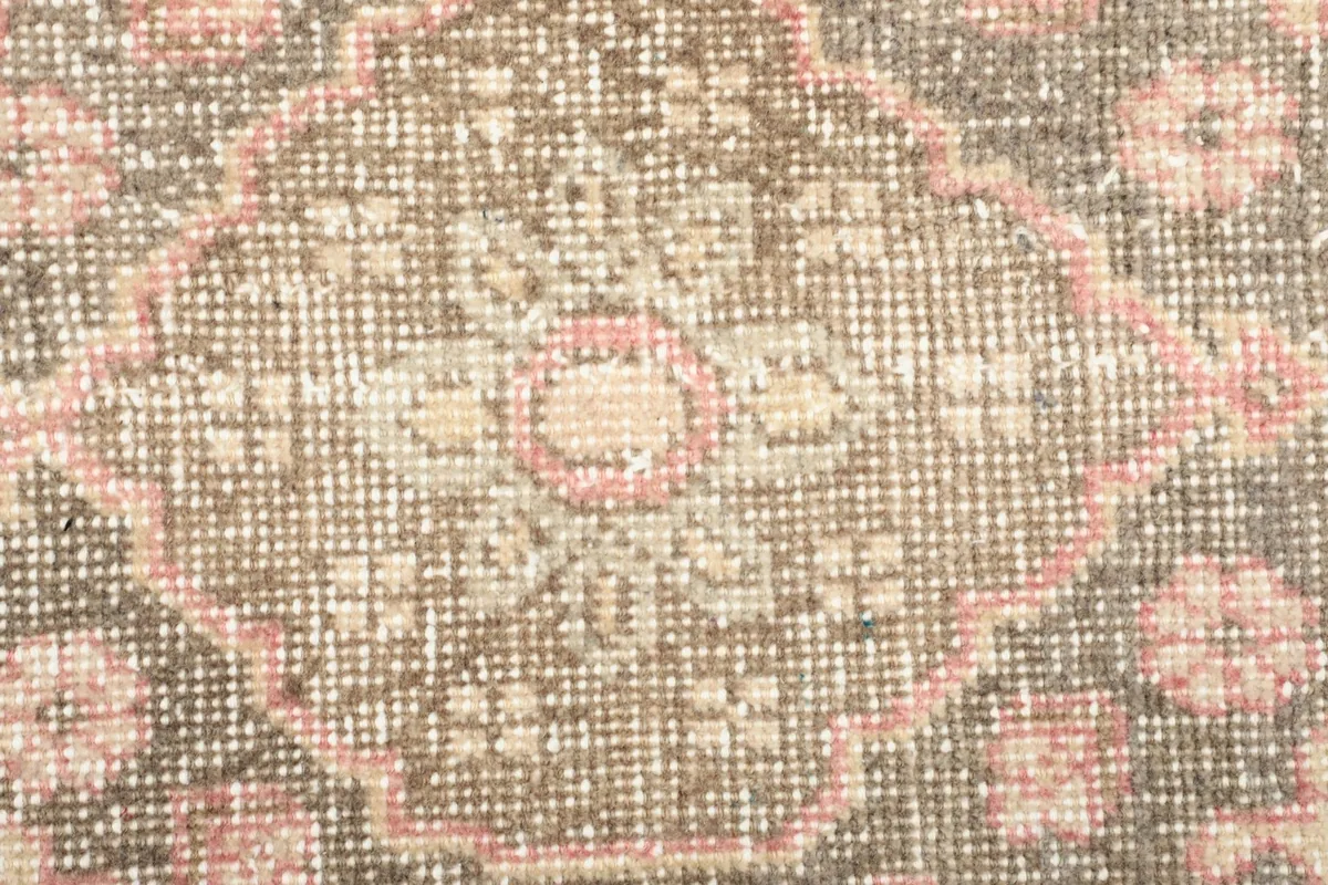 Close-up of the low wool pile and intricate knotting of the rose and brown medallion rug.