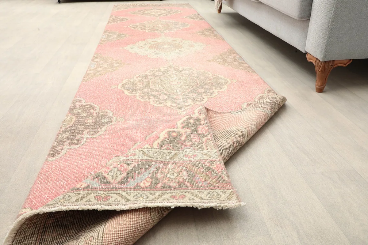View of the rose runner rug partially folded, showcasing its length and flexible structure.