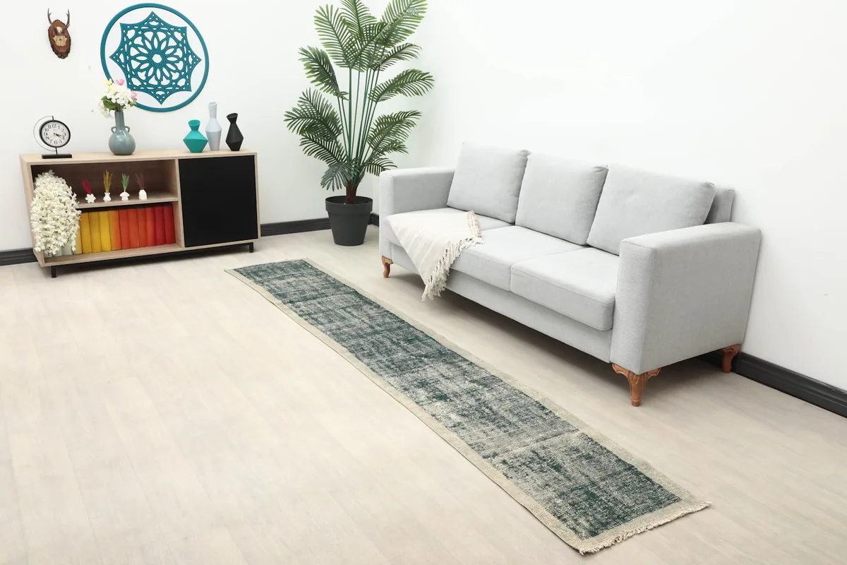 Long view of the distressed Anatolian runner rug in a living space with a sofa and shelving unit.
