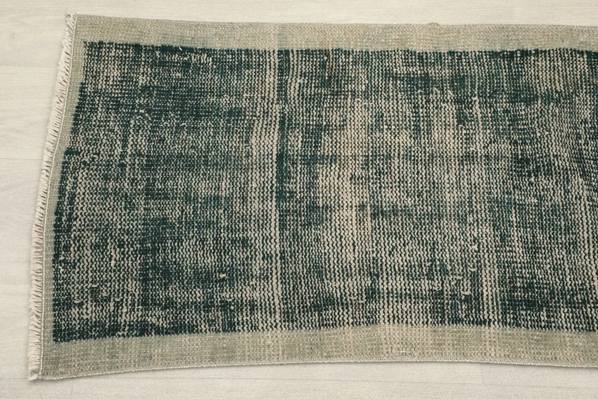 Close-up of the other end of the vintage runner, showing the faded green field and natural beige edge.