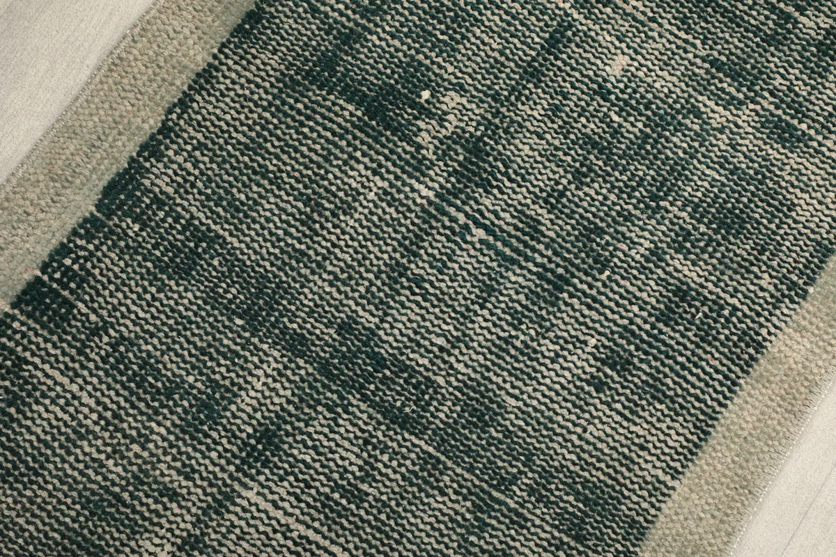 Detailed view of the low wool pile, showing the texture and variation in the green and cream colors.