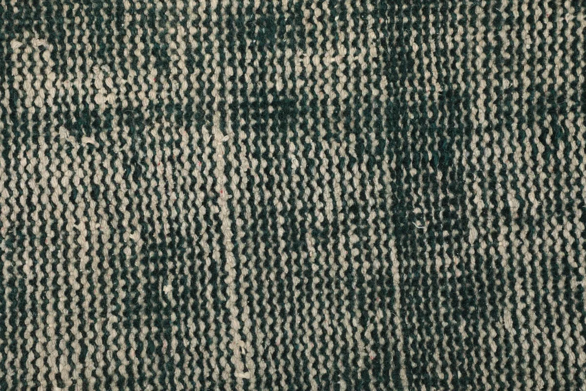 Macro shot of the hand-knotted wool pile, revealing the tight weave and distressed pattern.
