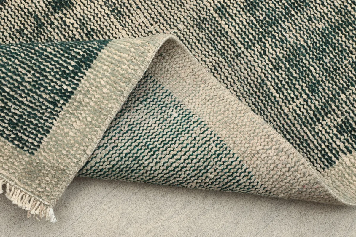 Folded corner of the rug displaying the sturdy cotton foundation and the reverse of the wool pile.