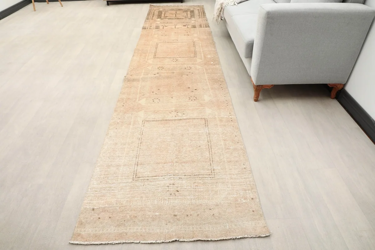 Vintage Anatolian runner rug extending down a hallway next to a light gray sofa