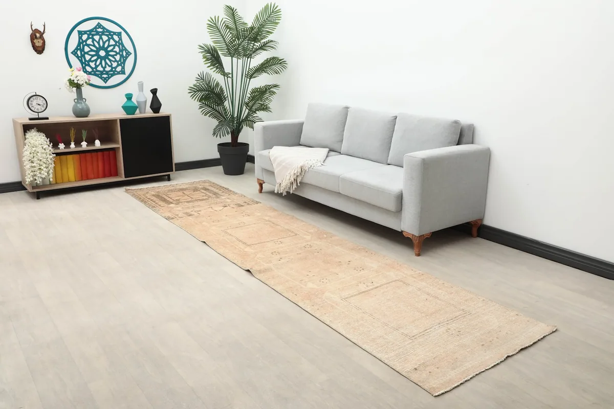 Long view of the beige runner rug in a living room setting with a sofa and decor