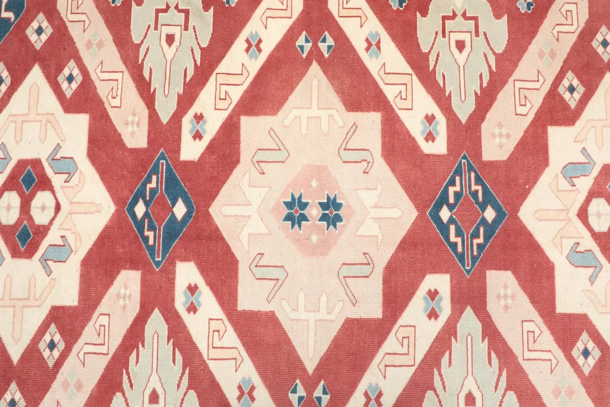 Detailed view of the central geometric medallion and surrounding motifs in red, ivory, and blue