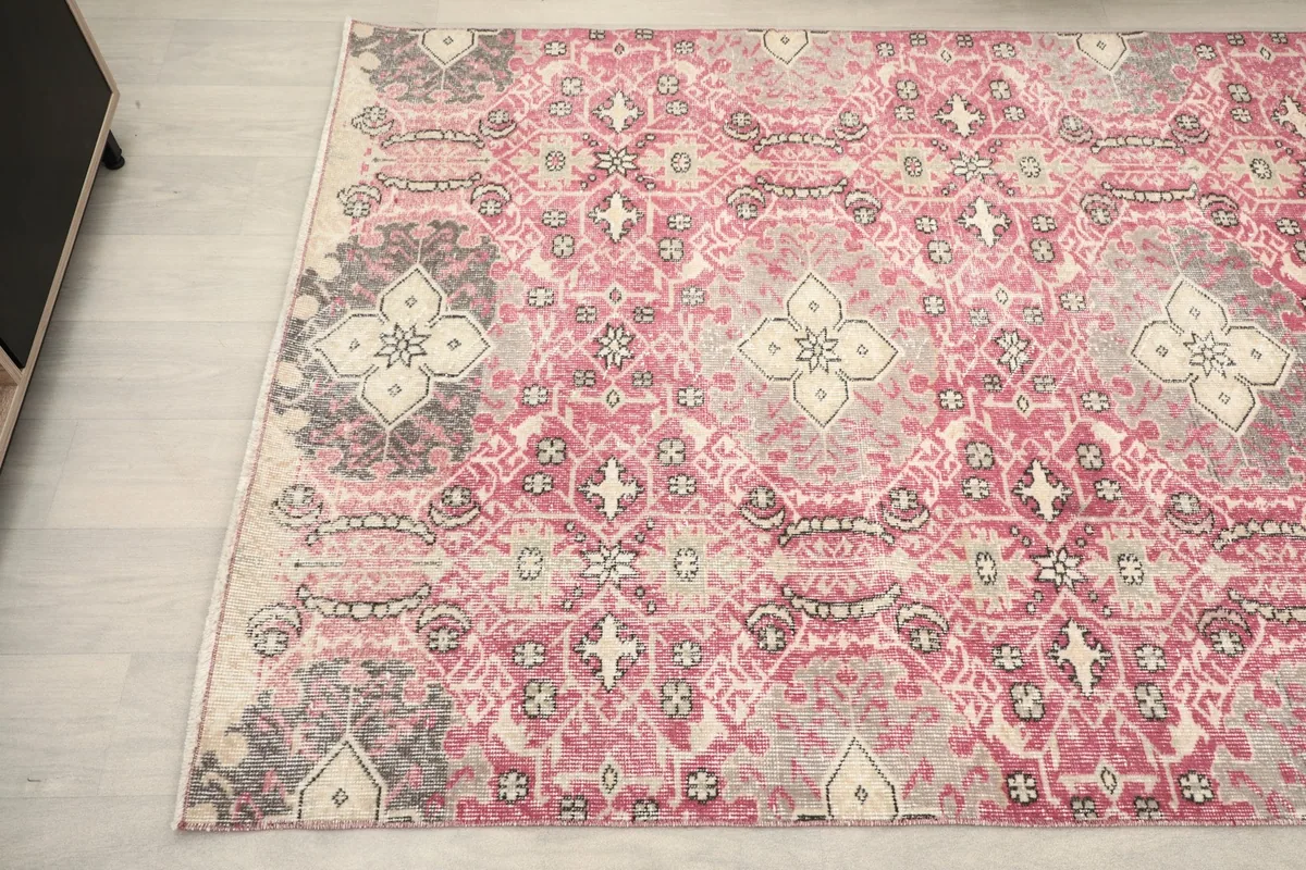 Corner view of the hand-knotted rug, highlighting the blend of rose, gray, and ivory colors