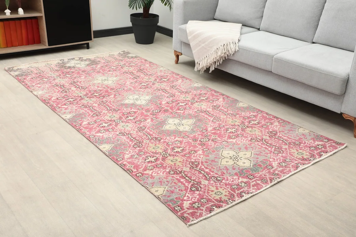 Close-up room view of the rose and gray Anatolian rug next to a gray sofa