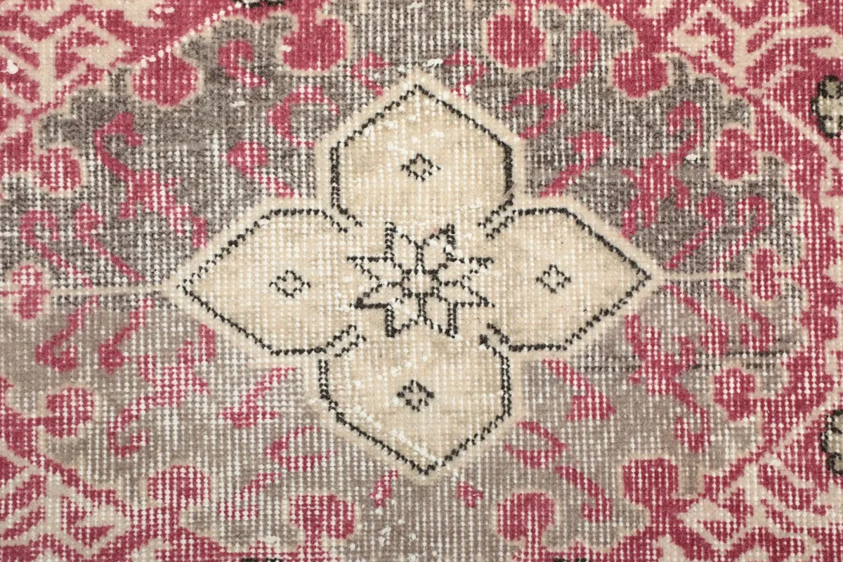 Close-up of a central medallion motif in ivory and black on a gray field
