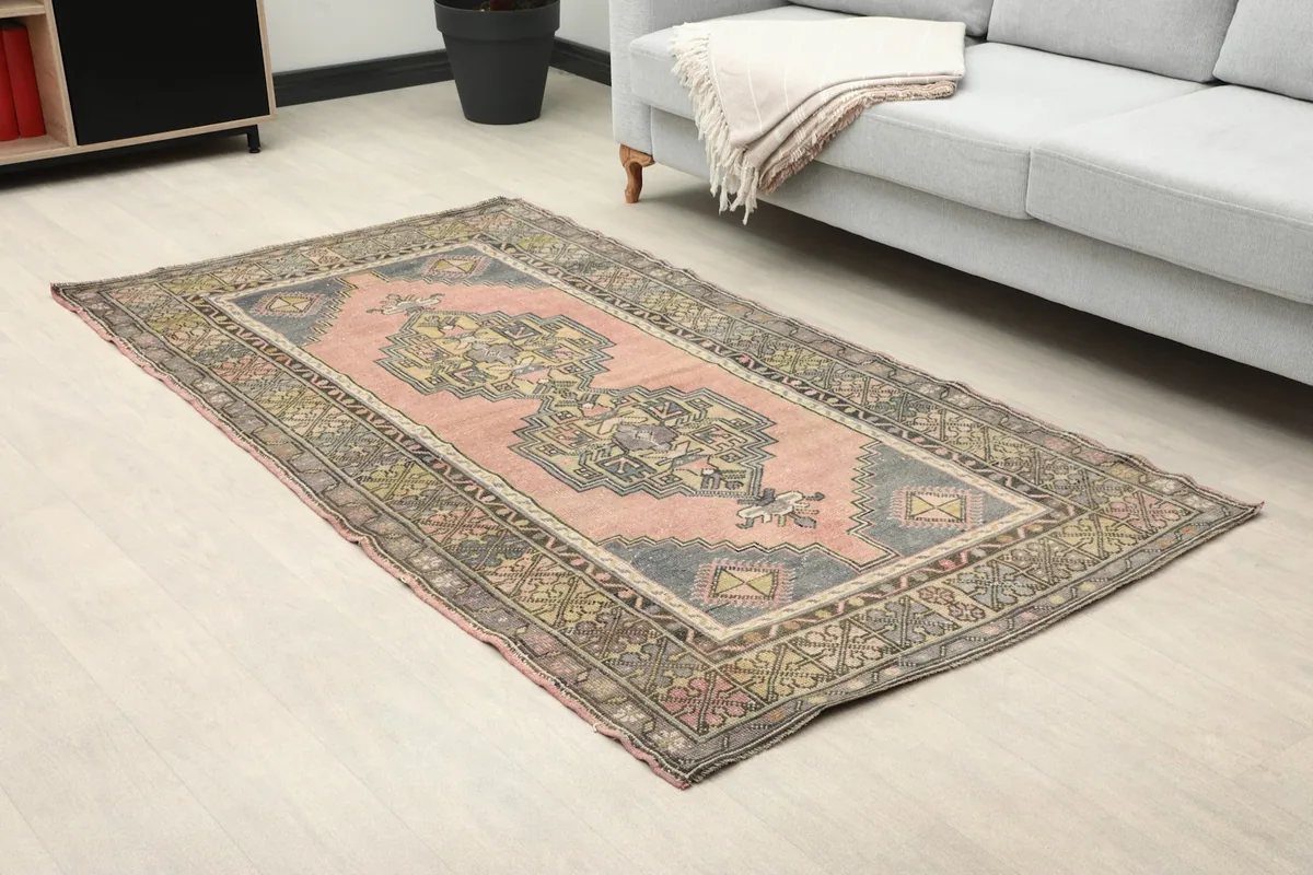 Angle view of the rose geometric rug in a living room, highlighting its placement next to a sofa.