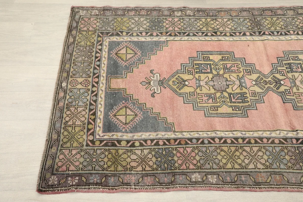 Close-up showing the corner of the rose rug, with its intricate border and central medallion design.