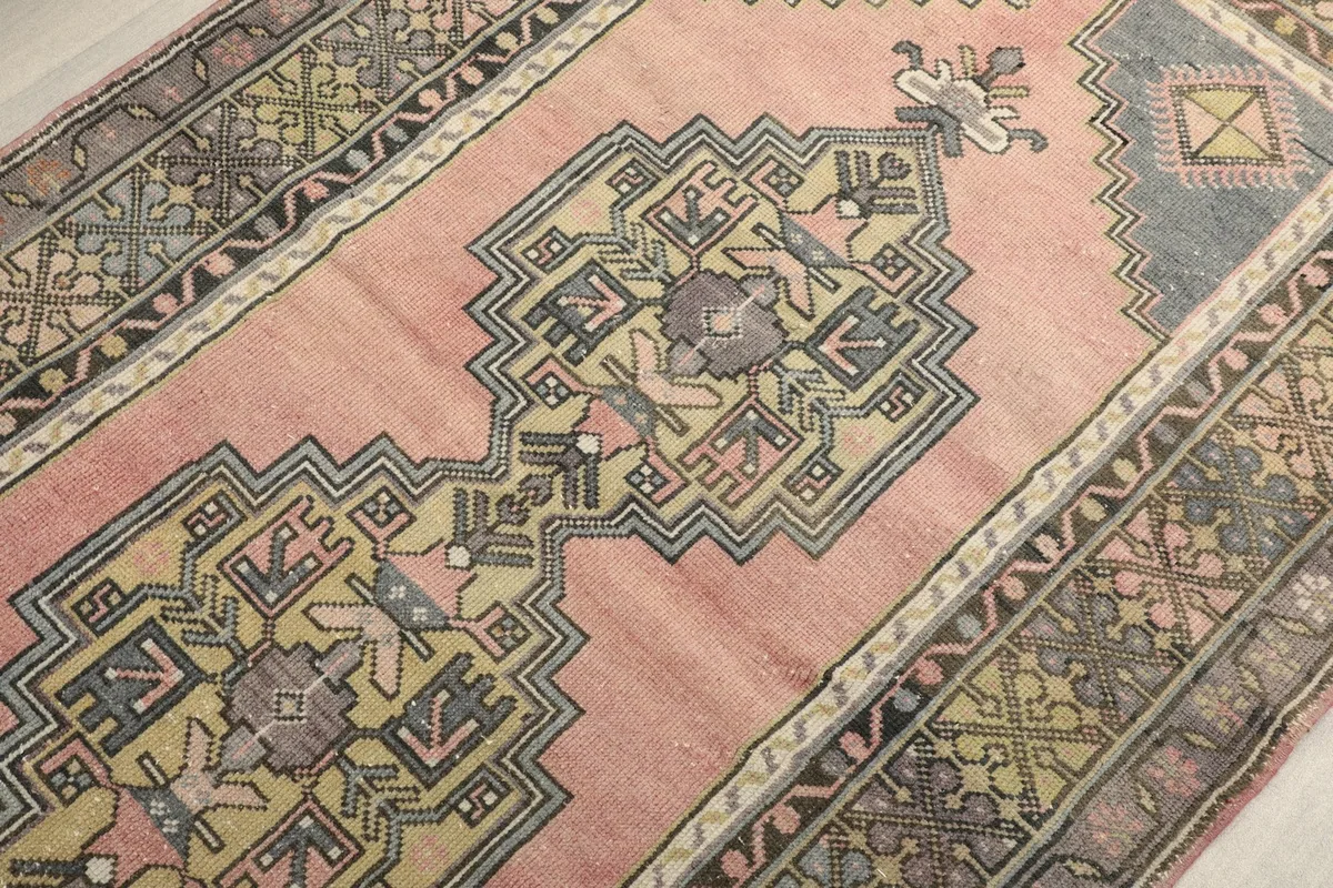 Detailed view of the central geometric medallion and surrounding patterns on the rose area rug.