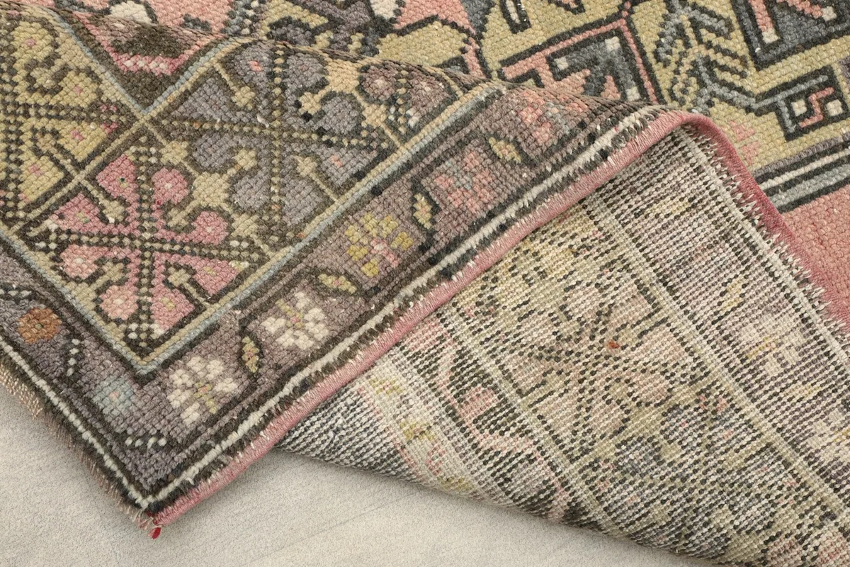 Close-up of the rug's edge and backside, revealing the cotton foundation and wool pile.