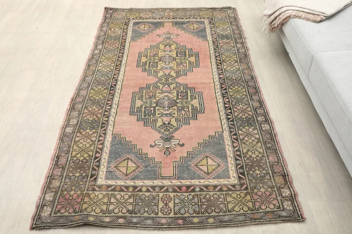 Overhead view of the rose geometric rug in a room setting, showing its colors and patterns.