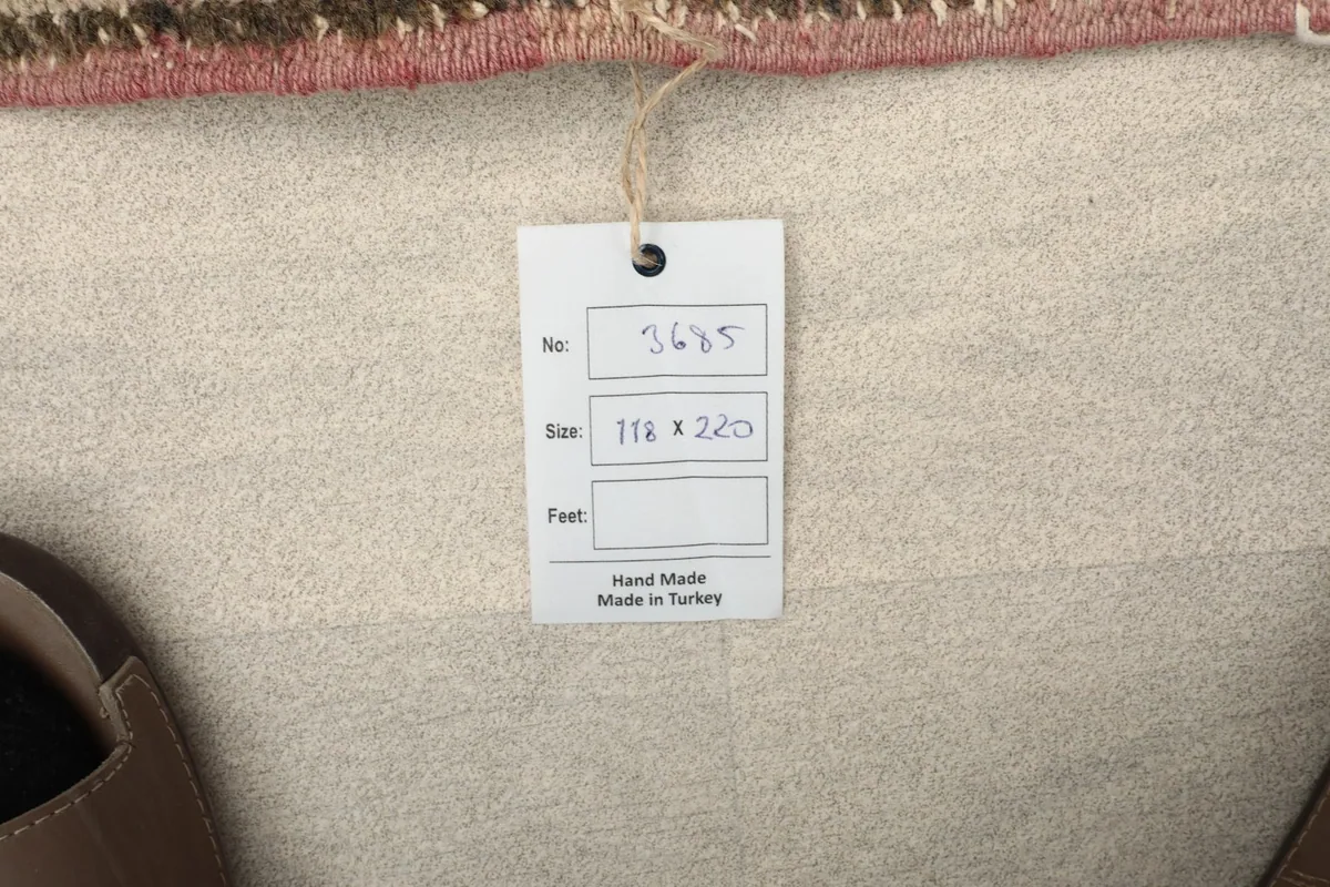 Product tag showing the rug's unique number and size in centimeters, confirming its handmade origin.