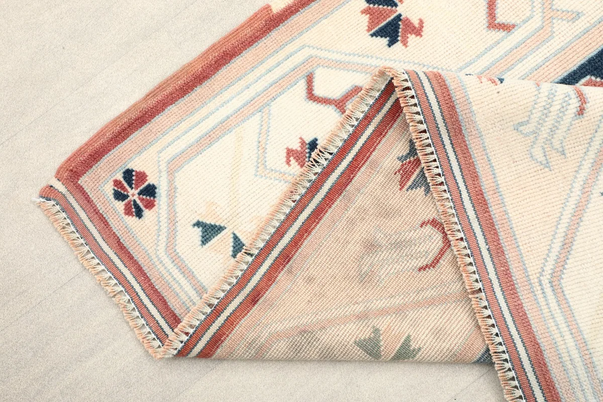 Rug folded to show the hand-knotted wool pile on cotton foundation and fringe