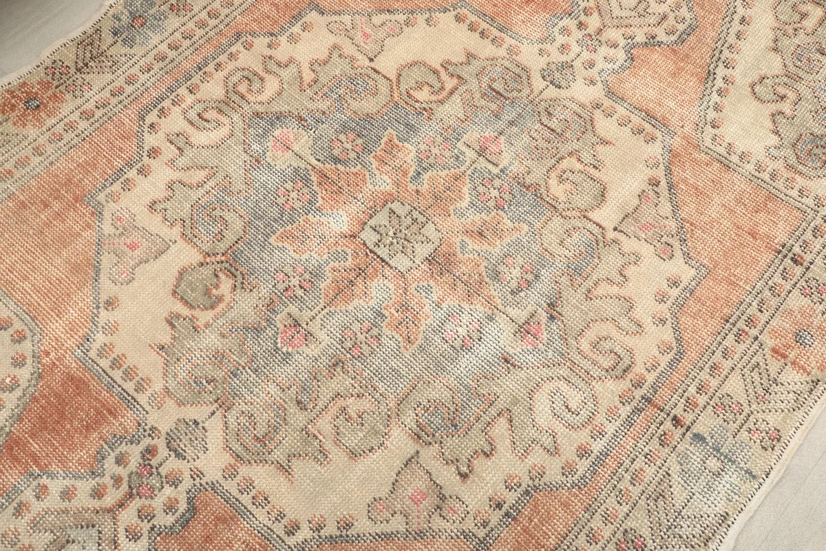 Close-up of the central medallion design with faded orange, blue, and beige tones