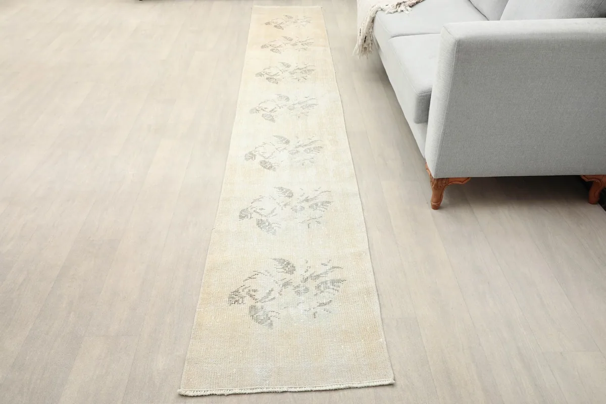 Runner rug placed in a room setting next to a sofa, highlighting its length and subtle design.