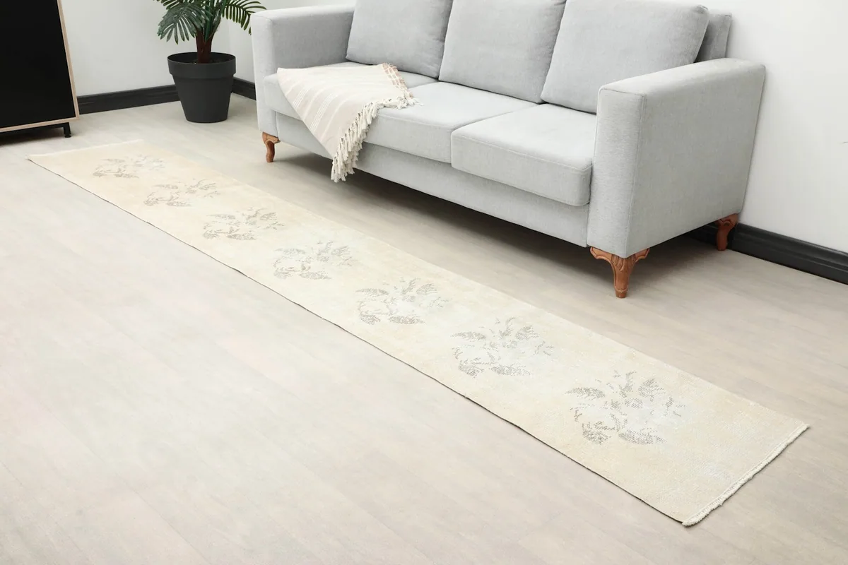 Angled view of the runner rug in a room, emphasizing its faded floral motifs and texture.