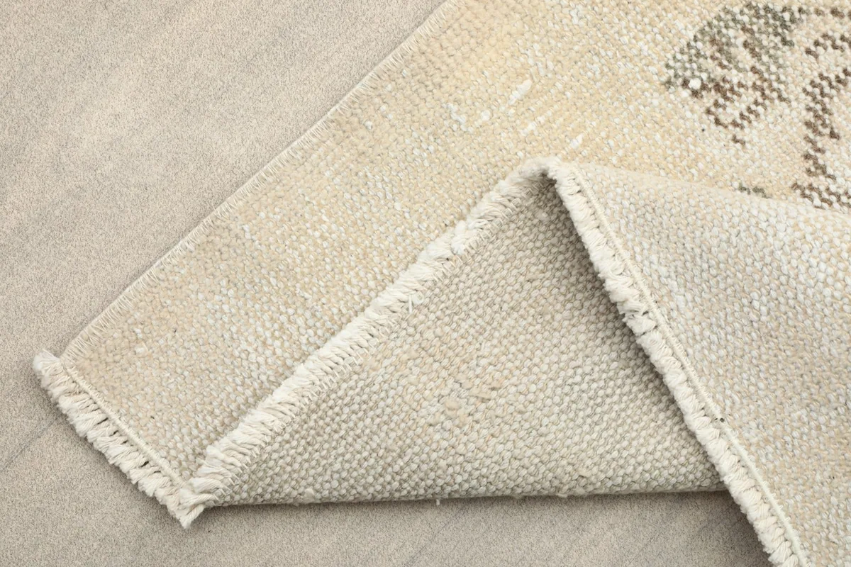 View of the rug's backside and folded edge, showing the cotton foundation and fringes.