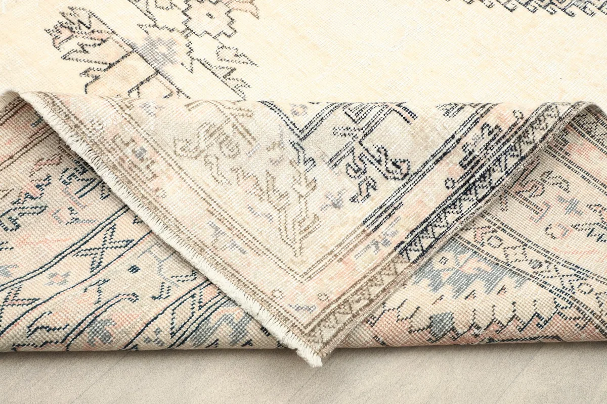 Folded corner revealing the back of the hand-knotted wool rug and cotton foundation.