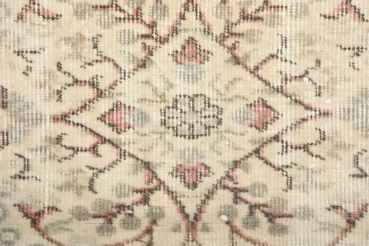 Close-up detail of the hand-knotted wool pile and intricate floral pattern with visible wear.