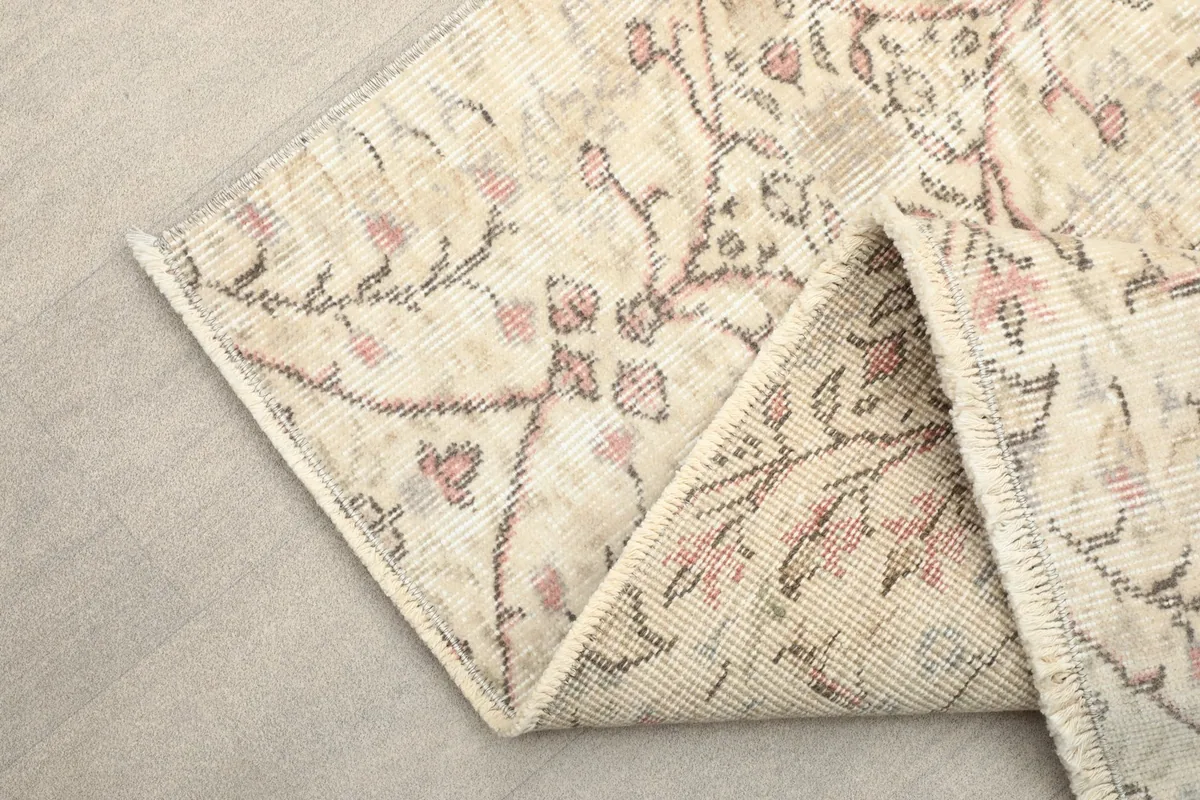 Folded corner of the ivory and rose vintage Anatolian rug, showing the reverse side and construction.