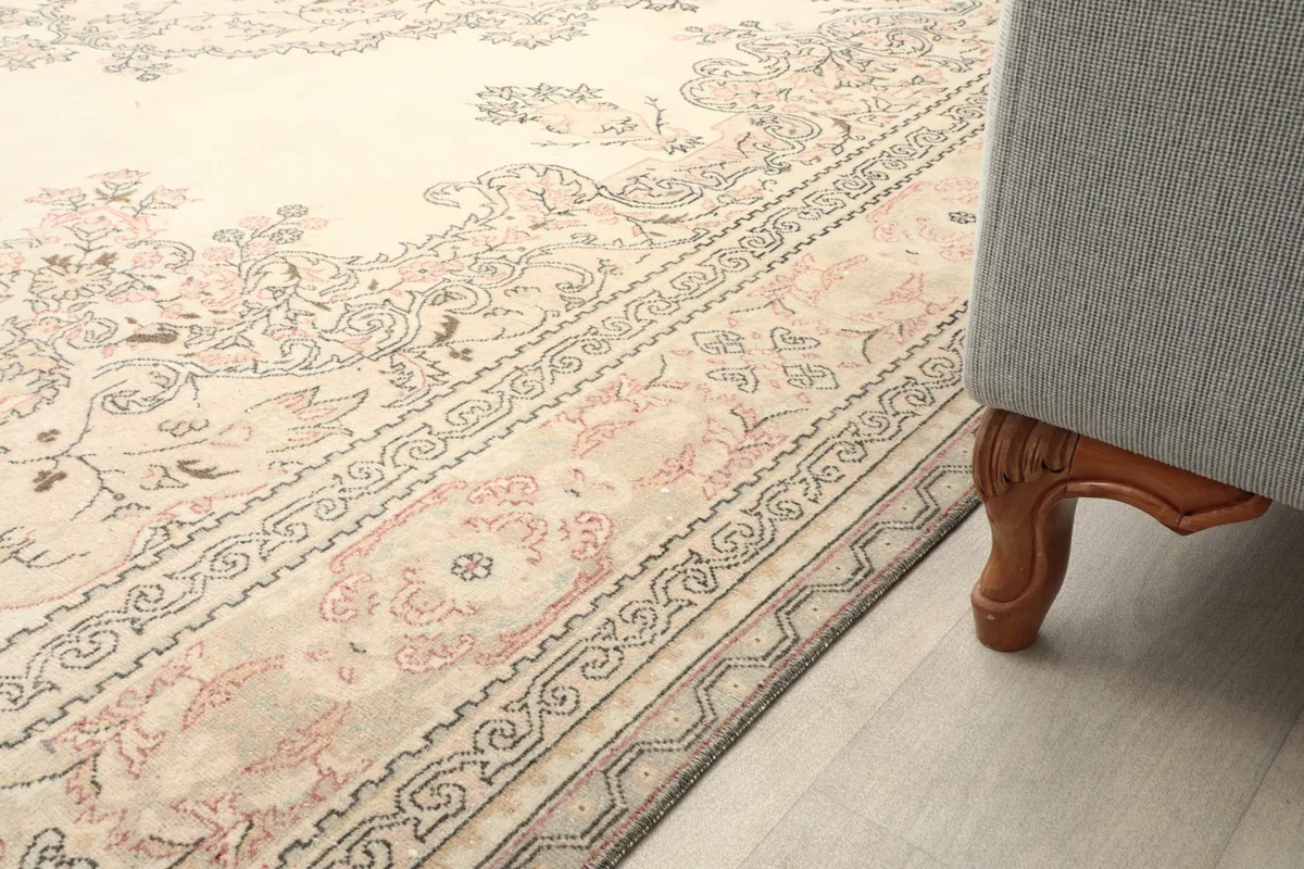 Detail of the rug next to a sofa leg, showing the border design and low pile