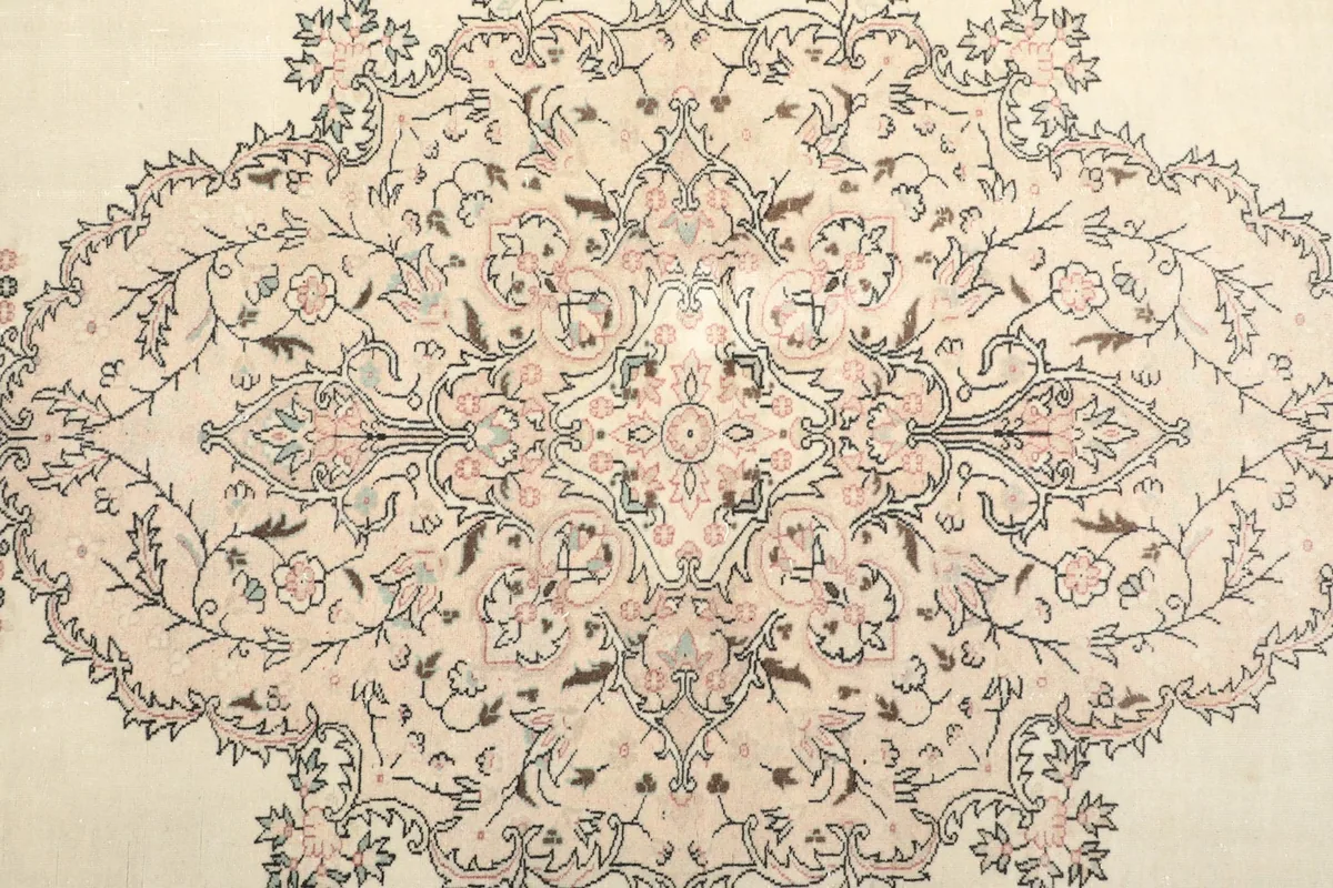 Detailed view of the central medallion with intricate rose and gray floral designs on an ivory field